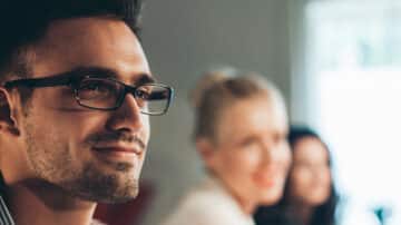 An experienced consultant smiling in a meeting with two others