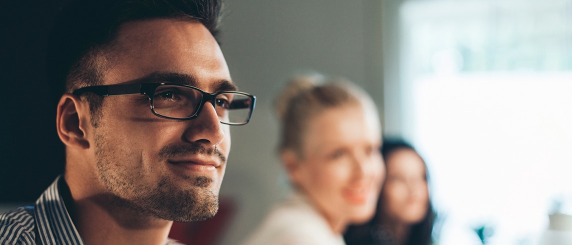An experienced consultant smiling in a meeting with two others