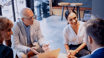 Four professionals sitting together in a positive meeting smiling