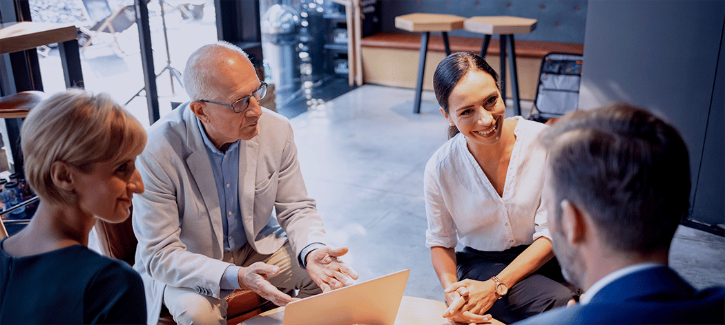 Four professionals sitting together in a positive meeting smiling