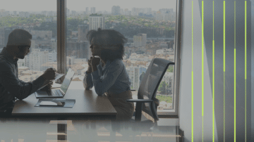 Modern business environment with a man and woman in front of window facing a city