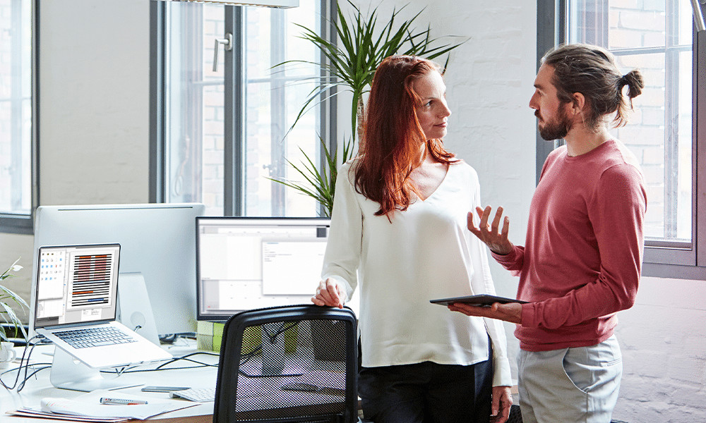 A man and a woman discussing work in the office.