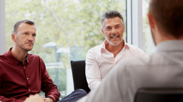 Two businessmen interviewing a consultant for a project.