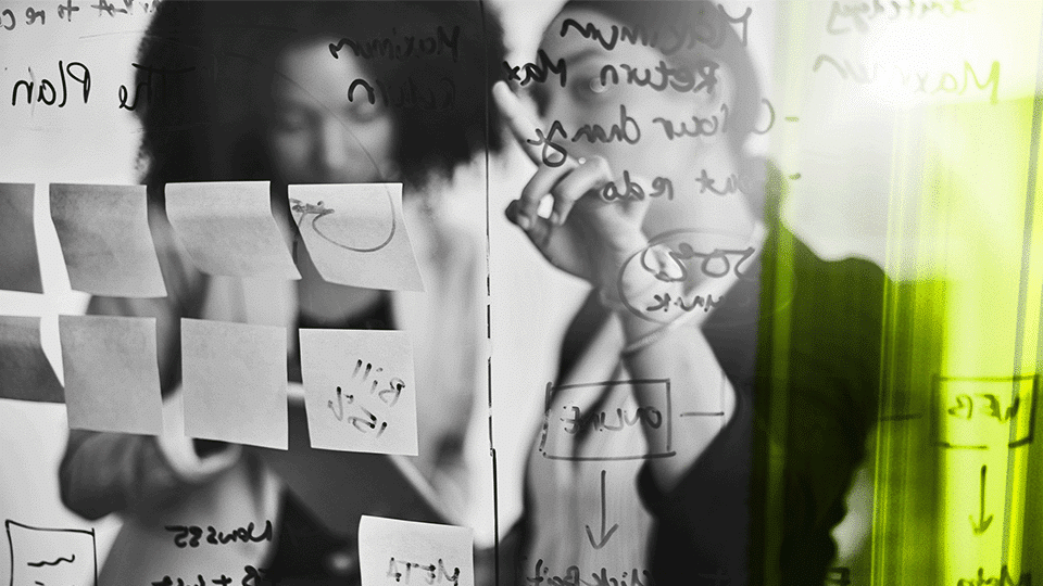Two consultants discussing on a transparent board with text and notes