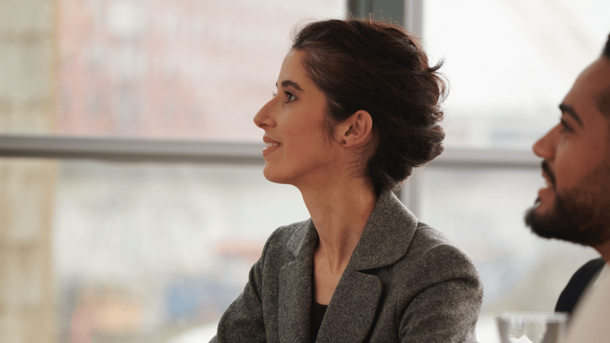 A young woman in a professional setting sitting in a meeting.